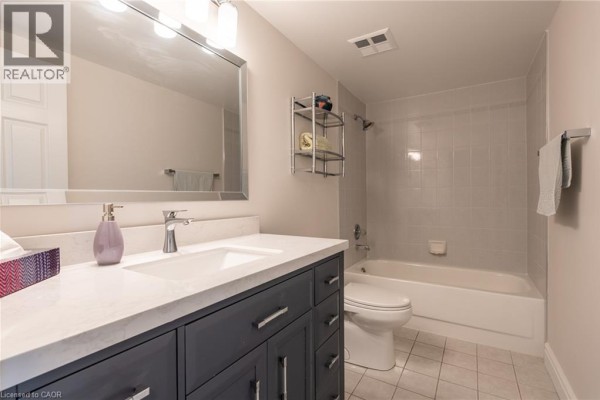 Modern bathroom vanity with sink, mirror, toilet, and bathtub with shower - 67 Caroline Street S Unit# 13a Hamilton