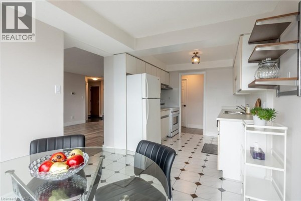 Glass dining table and kitchen with white appliances and geometric tiles - 67 Caroline Street S Unit# 13a Hamilton