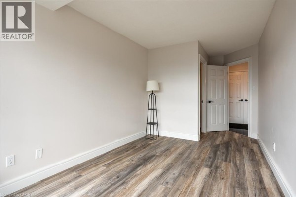 Wood-look flooring, white doors, and floor lamp in hallway - 67 Caroline Street S Unit# 13a Hamilton