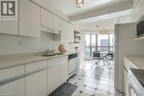 Kitchen with white cabinets, double sink, dishwasher, dining table, and city view - 67 Caroline Street S Unit# 13a Hamilton