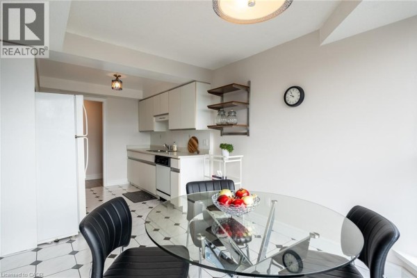 Kitchen with white cabinets, glass dining table, and black chairs - 67 Caroline Street S Unit# 13a Hamilton
