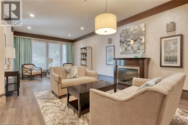 Living room with fireplace, sofas, and bookshelf - 67 Caroline Street S Unit# 13a Hamilton