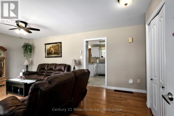 Living room with brown leather couches, a coffee table, and hardwood floors, leading to the kitchen. - 67 East Street E, Collingwood