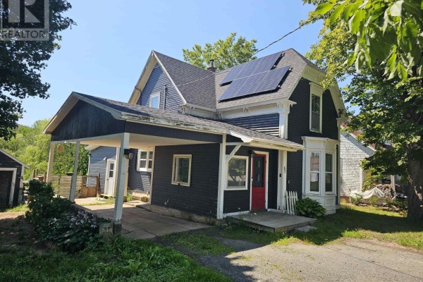 View of the dark-sided home with a covered carport and a black SUV. - 67 Lawrencetown Lane, Lawrencetown