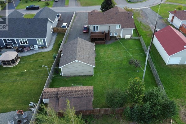 Aerial view of the backyard with a wooden deck, lawn, detached garage, and shed. - 67 Marshalls Drive, Bishop S Falls
