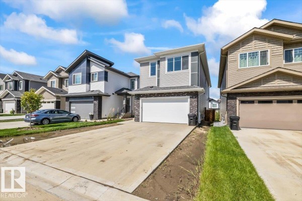 Street view of a row of modern two-story houses with attached garages. - 67 Meadowgrove Ln, Spruce Grove