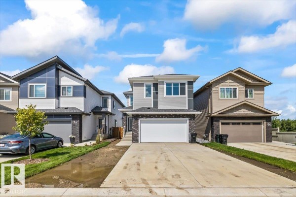 Street view of a row of modern two-story houses with attached garages. - 67 Meadowgrove Ln, Spruce Grove