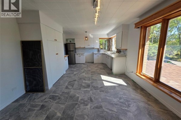 Spacious kitchen with white cabinets, stainless steel refrigerator, and bay windows. - 67 Narcisse-beaulieu Street, Edmundston