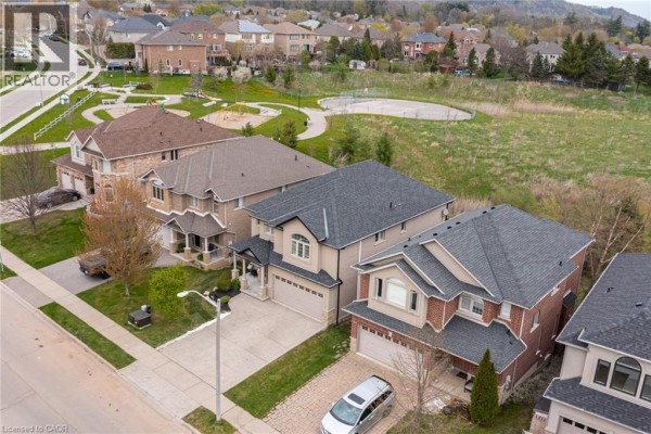 High-angle aerial shot of the street showing multiple houses and a park on the right side. - 67 Newcombe Road, Dundas
