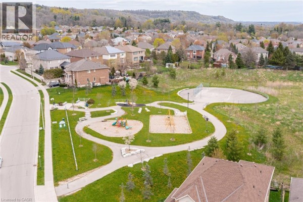 Overhead view of a suburban park with a playground, basketball court, and walking paths next to houses. - 67 Newcombe Road, Dundas