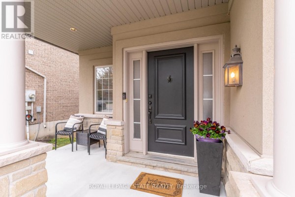 Close-up of a front porch with a dark grey door, seating, and decorative planter. - 67 Newcombe Road, Hamilton