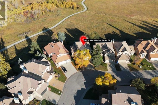 Aerial view of a suburban street with several houses and a pathway behind them. - 67 Suncanyon Park Se, Calgary