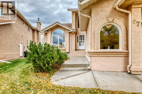 Exterior detail of the house entrance with arched windows and concrete walkway. - 67 Suncanyon Park Se, Calgary