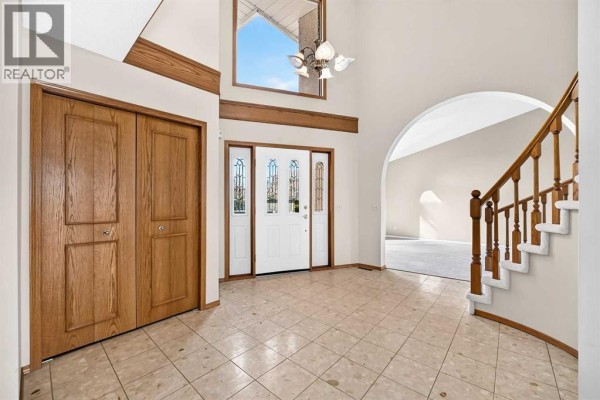 Interior view of a foyer with tile flooring, a large closet, and a staircase. - 67 Suncanyon Park Se, Calgary