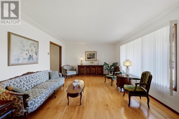 Living room with white walls, hardwood floors, floral sofa, and antique furniture. - 67 Westridge Rd, Sault Ste  Marie