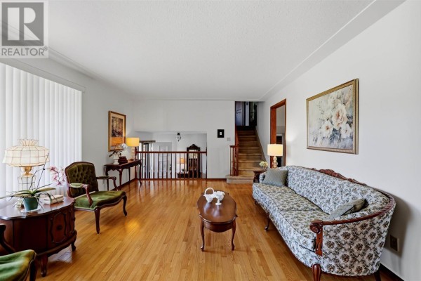 Living room and staircase with white walls, hardwood floors, and dark wood banisters. - 67 Westridge Rd, Sault Ste  Marie