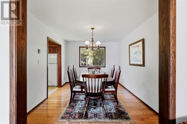 Dining room with wooden table and chairs, patterned rug, and a window view. - 67 Westridge Rd, Sault Ste  Marie