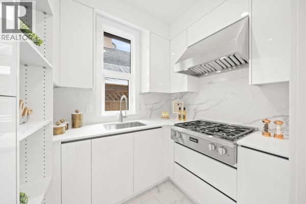 Galley kitchen with white cabinets, stainless steel range, and marble backsplash. - 6700 Francis Road, Richmond