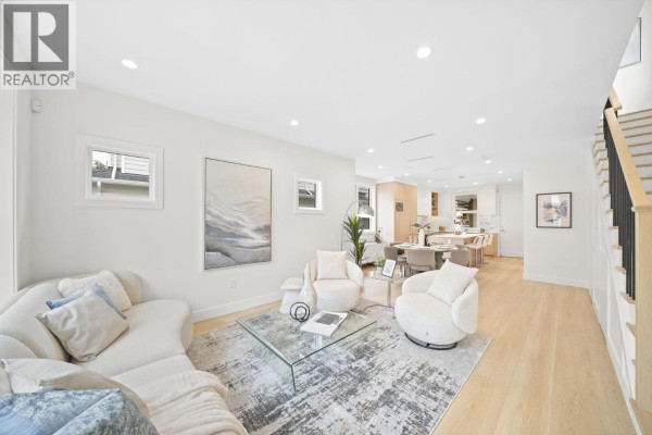 Living room with a curved sofa, accent chairs, glass coffee table, and view of the dining area. - 6700 Francis Road, Richmond