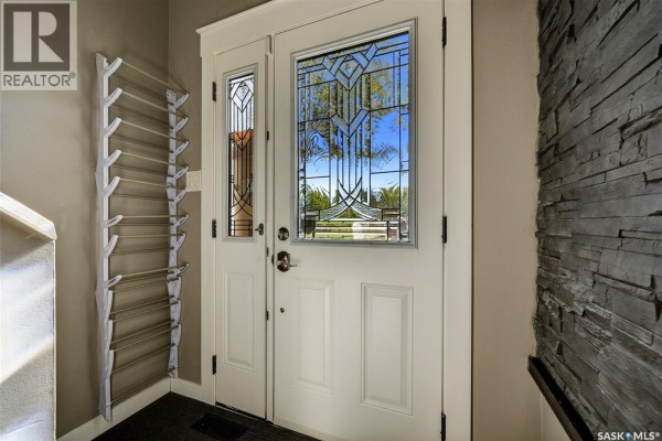 Close-up of a white double front door with leaded glass sidelights and a stone accent wall. - 6702 Whelan Drive, Regina