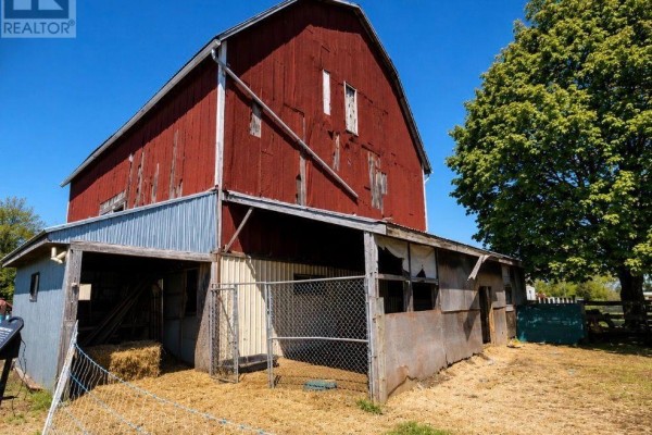 Side view of a large red barn with a metal roof and attached weathered structures. - 6703 Pine Plains Road E, Adjala Tosorontio