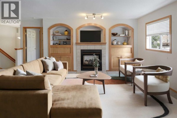 Living room with grey carpet, fireplace, and built-in oak cabinets and shelving. - 6711 Pinecliff Grove Ne, Calgary