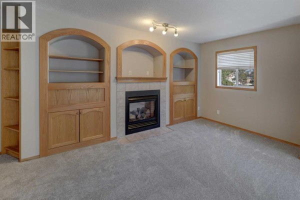 Open concept living area and kitchen with grey carpet, oak cabinetry, white appliances, and a ceiling fan. - 6711 Pinecliff Grove Ne, Calgary