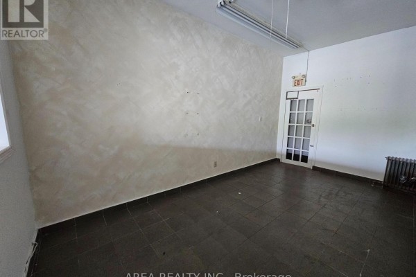 Corner of a commercial space with an exit door and a radiator. - 672 Sheppard Avenue W, Toronto