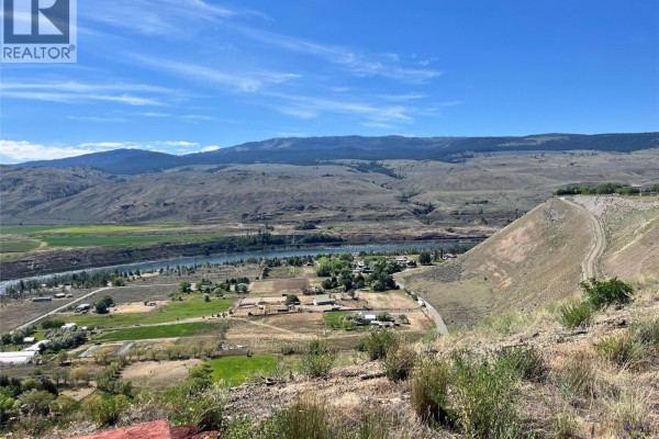Panoramic view of a wide river valley with farmland, distant mountains, and a clear blue sky. - 6736 Pinecrest Drive, Kamloops
