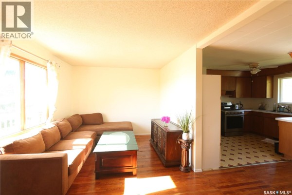 Living room with a large brown sectional sofa, wooden coffee table, and a glimpse of the kitchen with wooden cabinets. - 675 Fort San Road, Fort San