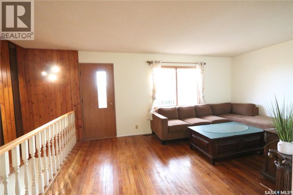 Living room with a large brown sectional sofa, a dark wooden coffee table, and a window with sheer curtains. - 675 Fort San Road, Fort San