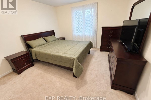 Bedroom with queen bed, two nightstands, dresser, and mirror against a light beige wall. - 675 Waverly Street N, Oshawa