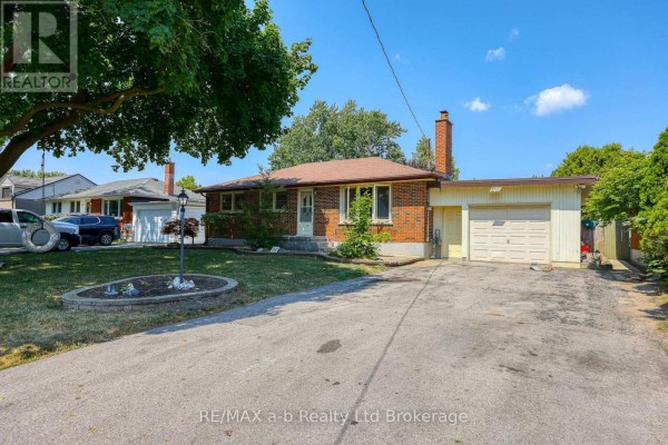 Side view of a brick bungalow with an attached garage and a concrete driveway. - 6752 Beattie Street, London South