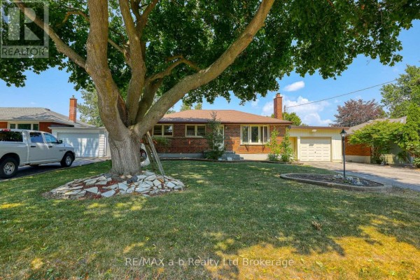 Wide angle exterior front view of a brick bungalow from the lawn with a large tree. - 6752 Beattie Street, London South