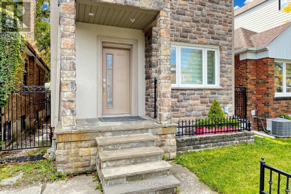 Close-up of the front entrance with stone steps, a beige door, and a small garden bed. - 676 Vaughan Road, Toronto