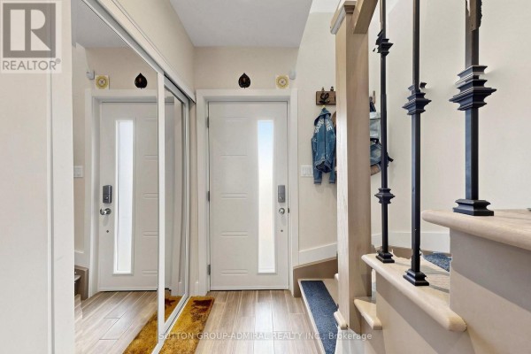Interior foyer with two white doors, mirrored closet doors, and a light wood floor. - 676 Vaughan Road, Toronto