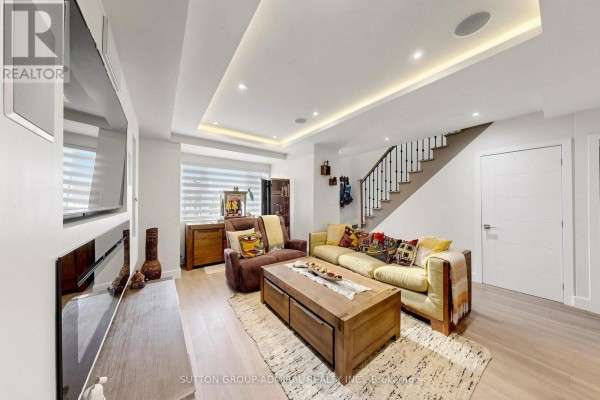 Living room with a sectional sofa, large wooden coffee table, and a sunken ceiling with pot lights. - 676 Vaughan Road, Toronto
