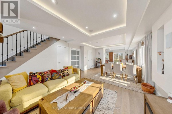 Open-concept living and dining area with a large yellow sofa, dining table with chairs, and natural light. - 676 Vaughan Road, Toronto