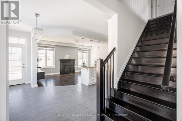 View into an open-concept living area with dark hardwood floors, a fireplace, and a kitchen island. - 677 Broad Cove Crescent, Ottawa