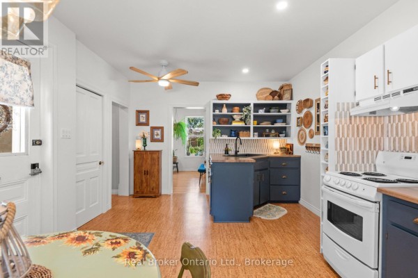 Kitchen with navy blue cabinets, butcher block countertops, white appliances, and open shelving displaying various decor items. - 677 Garafraxa Street N, West Grey