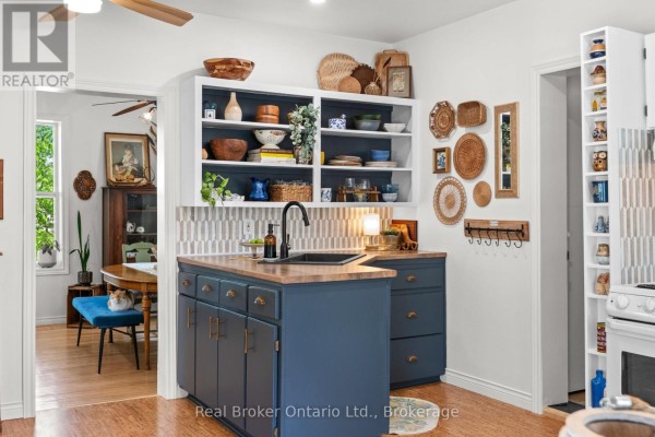 Kitchen with navy blue cabinets, butcher block countertops, white appliances, and open shelving displaying various decor items. - 677 Garafraxa Street N, West Grey