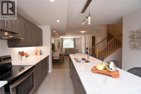 Open concept kitchen and living area with hardwood stairs and dining table. - 677 Park Road N Unit# 2, Brantford