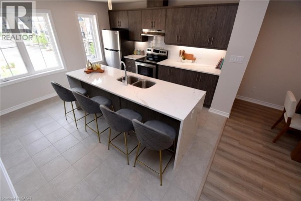 Aerial view of a kitchen with island, bar stools, and open doorway to dining area. - 677 Park Road N Unit# 2, Brantford