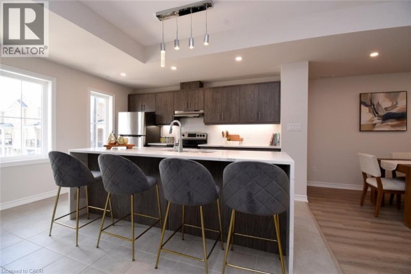 Kitchen island with bar stools, view towards dining area with a table and chairs. - 677 Park Road N Unit# 2, Brantford