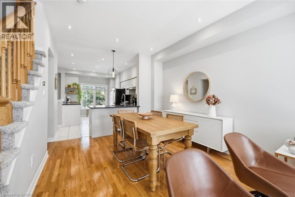 White tiled kitchen with stainless steel appliances and a large window overlooking trees. - 678 Rowley Common, Burlington