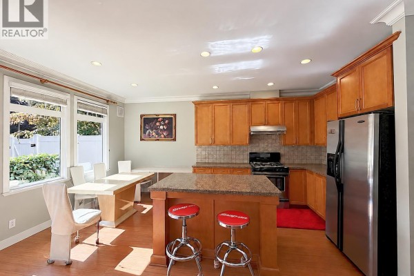 Kitchen with light wood cabinets, island, granite counters, and stainless steel appliances. - 6780 Lynas Lane, Richmond