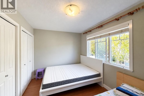 Bedroom with queen bed, white headboard, and closet doors. - 6780 Lynas Lane, Richmond