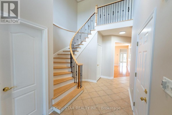Interior foyer with a curved staircase featuring wooden steps and black metal railings. - 6782 Kazoo Court, Mississauga