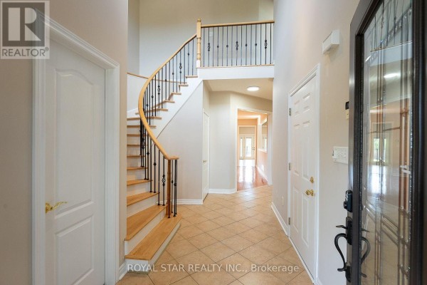 Interior foyer and hallway showing a curved staircase, tiled floor, and wooden doors. - 6782 Kazoo Court, Mississauga