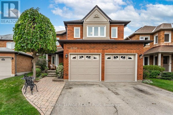 Front facade of a red brick house with two beige garage doors and a peaked roof detail. - 6795 Gracefield Drive, Mississauga
